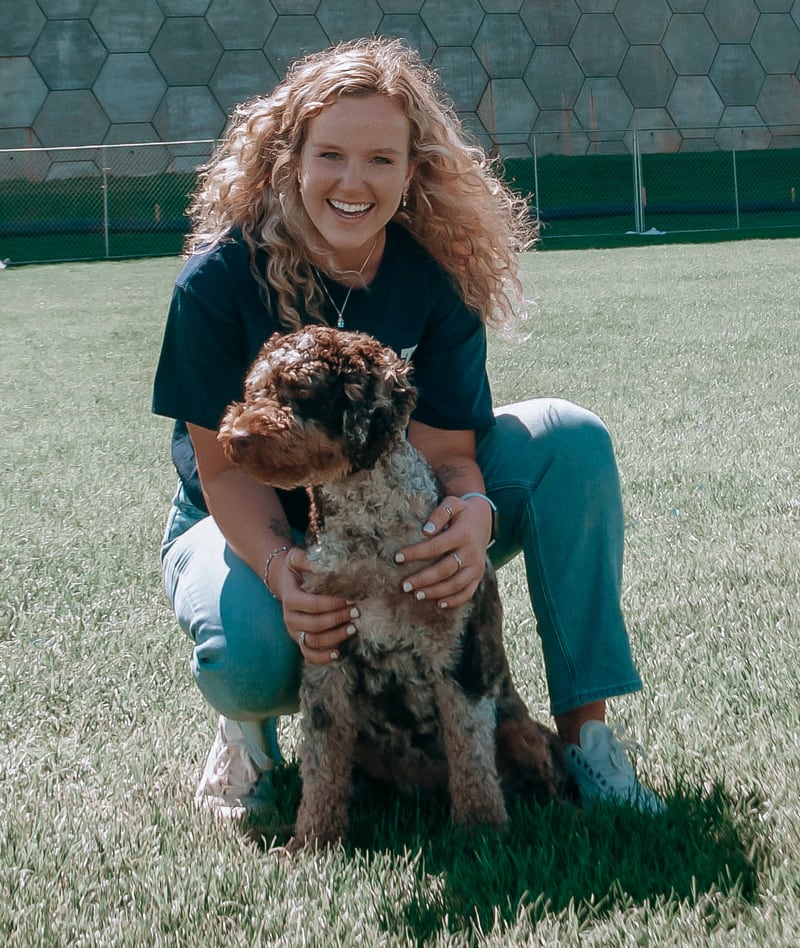 Coach is smiling and posing with her dog.